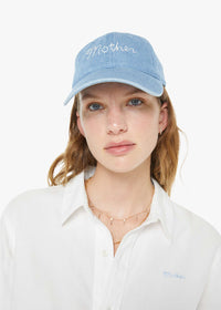Woman wearing a light blue cap with 'Mother' embroidered on it against a white background
