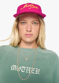 Person wearing a pink cap and green sweatshirt with 'Mother' branding on a white background