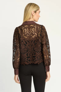 A woman shown from the back wearing a brown sheer lace jacket with an ornate damask pattern over black pants, against a plain light gray studio background.
