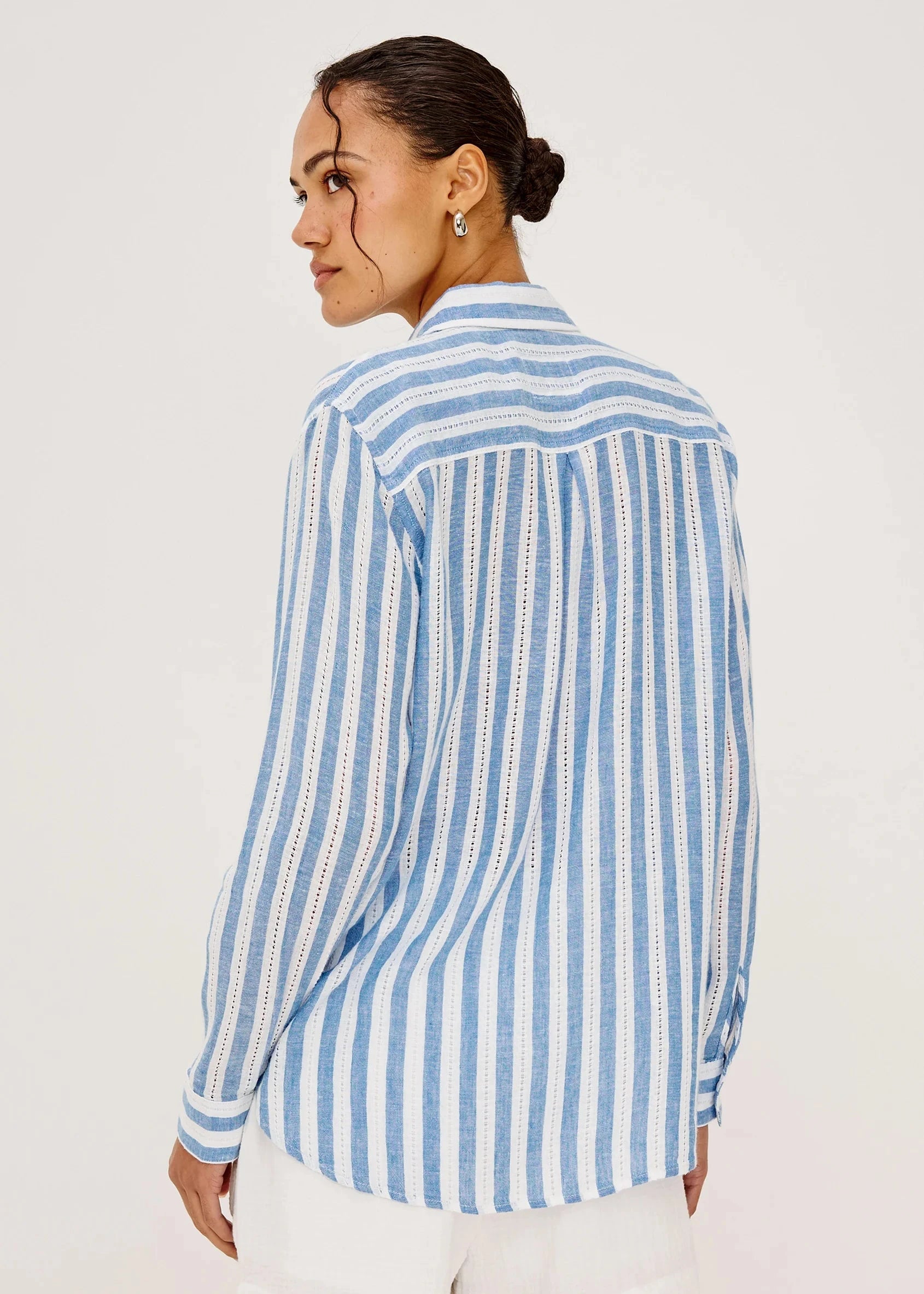 Woman wearing a blue and white striped shirt on a plain background