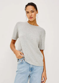 Woman wearing a gray t-shirt and light blue jeans against a white background
