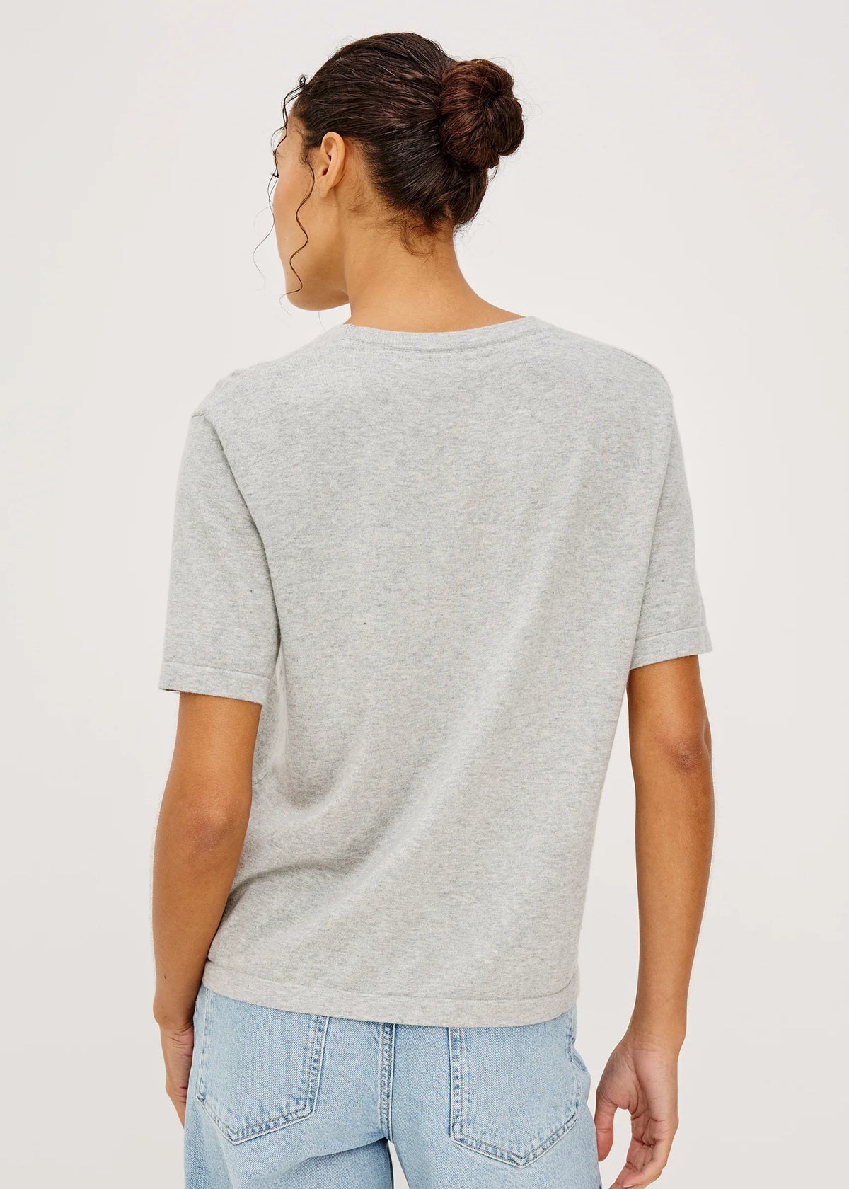 Person wearing a gray t-shirt and light blue jeans on a plain background