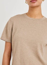 Close-up of a person wearing a beige t-shirt against a white background