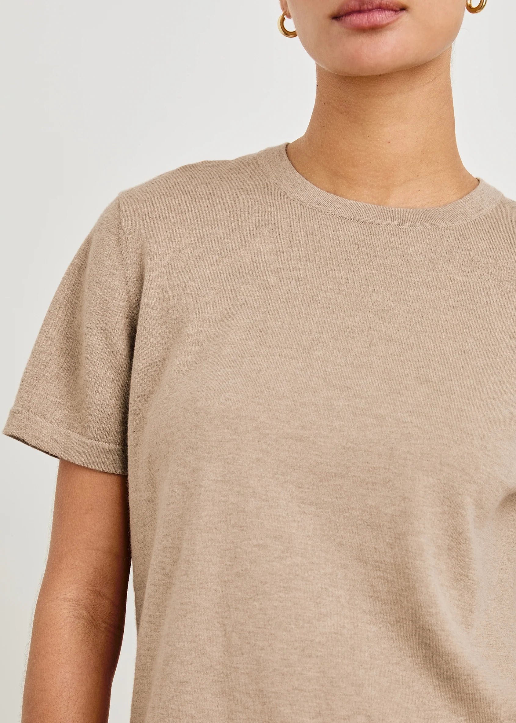 Close-up of a person wearing a beige t-shirt against a white background