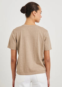 Person wearing a beige t-shirt and white pants on a light gray background