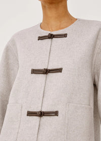 Close-up of a light gray coat with dark brown buttons on a neutral background