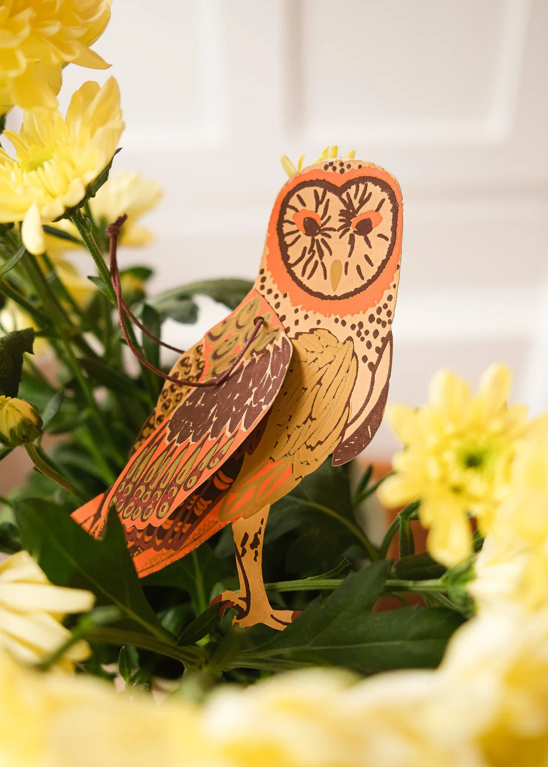 Decorative owl figure among yellow flowers