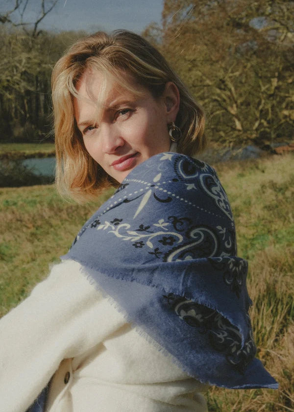 Woman wearing a blue patterned shawl in a natural setting