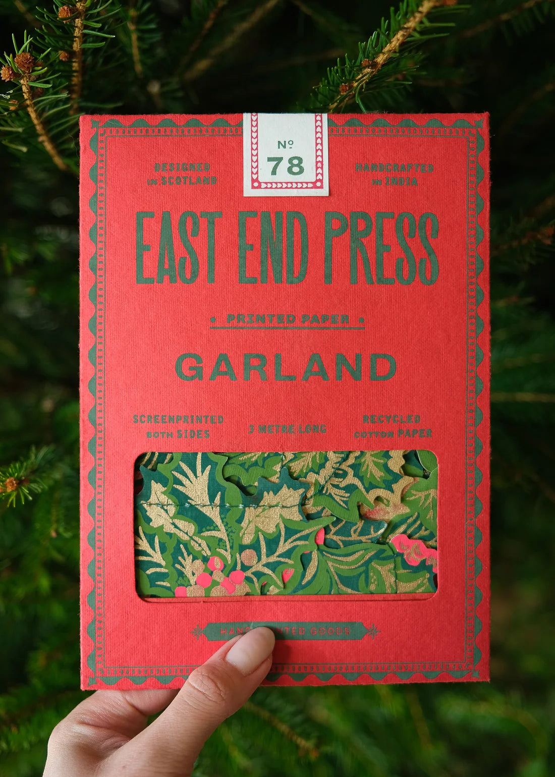 Red box with green floral design held against a green leafy background