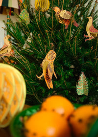 Decorative Christmas tree with bird ornaments and tangerines on a table