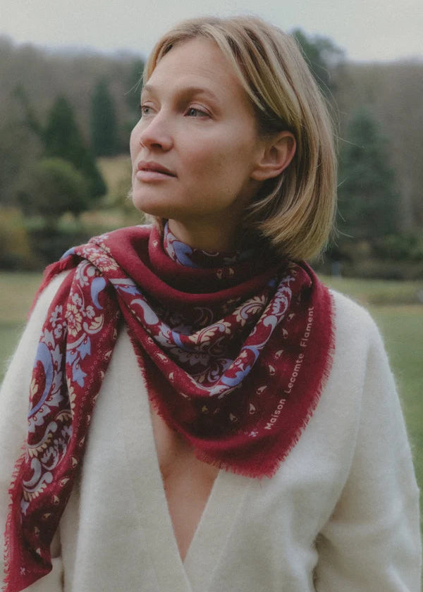 Woman wearing a patterned scarf outdoors with trees in the background