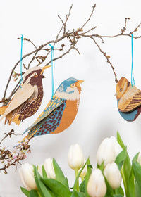 Decorative birds hanging from a branch with white tulips below
