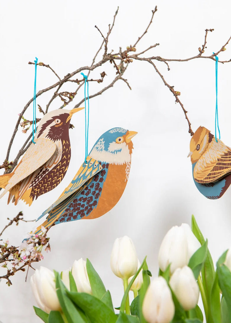 Decorative birds hanging from a branch with white tulips below