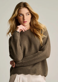 Woman wearing a brown knitted sweater against a plain background
