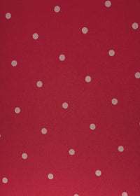 A close-up of a red fabric or material surface with evenly spaced small white polka dots.