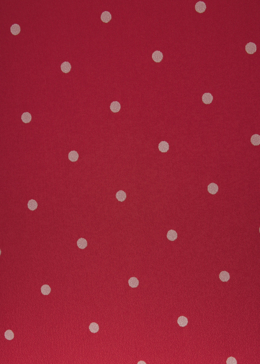 A close-up of a red fabric or material surface with evenly spaced small white polka dots.