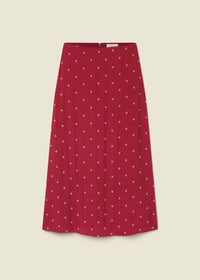 A red A-line skirt with a small white polka dot pattern, shown flat against a light beige background.