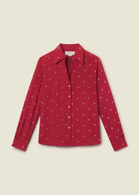 A red long-sleeve button-up shirt with a small white polka dot pattern, displayed flat against a light beige background.