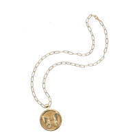 Gold necklace with a round pendant on a white background