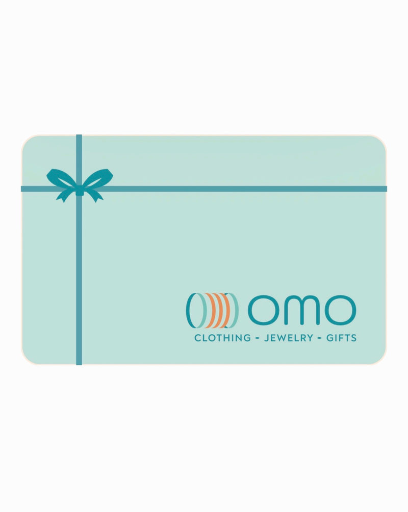 A mint green gift card with a teal ribbon graphic and the 'omo' logo, featuring the text 'CLOTHING - JEWELRY - GIFTS' on a white background.