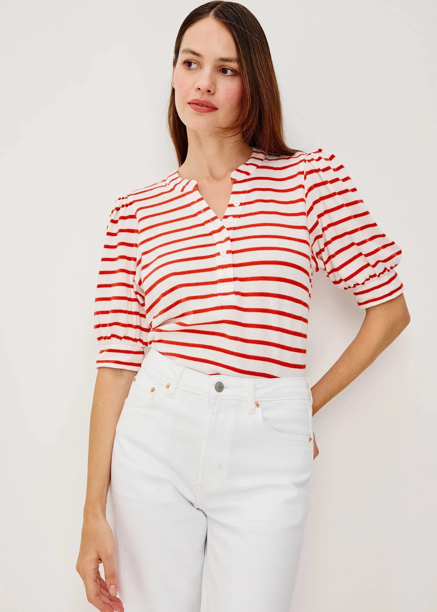 Woman wearing a red and white striped shirt with white pants on a plain background
