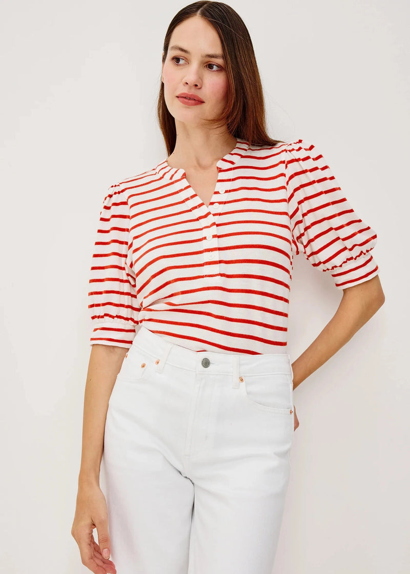 Woman wearing a red and white striped shirt with white pants on a plain background