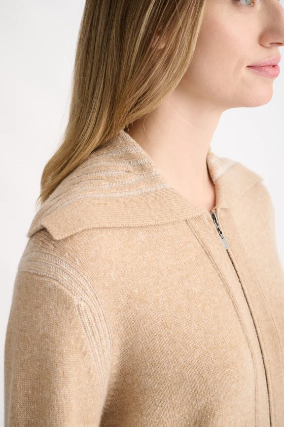 Close-up side view of a woman wearing a beige knit zip-front top with a wide collar and subtle textured stripe details on the shoulder.