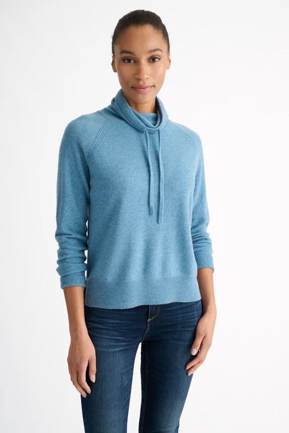 Woman wearing a blue sweater and jeans on a white background