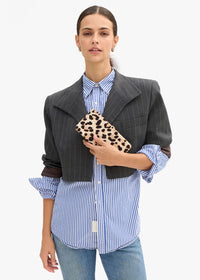 A model wearing a dark gray cropped pinstripe blazer over a blue and white striped button-down shirt, holding a leopard-print clutch bag, set against a plain white background.