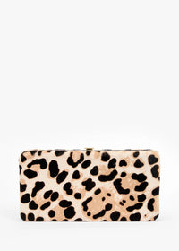 A leopard print clutch purse with black spots on a beige and light brown background, photographed against a plain white studio background.