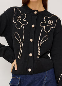 Black cardigan with floral embroidery on a plain background