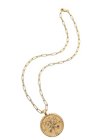A gold chain necklace with a round pendant featuring a floral and cross motif, displayed on a clean white background.