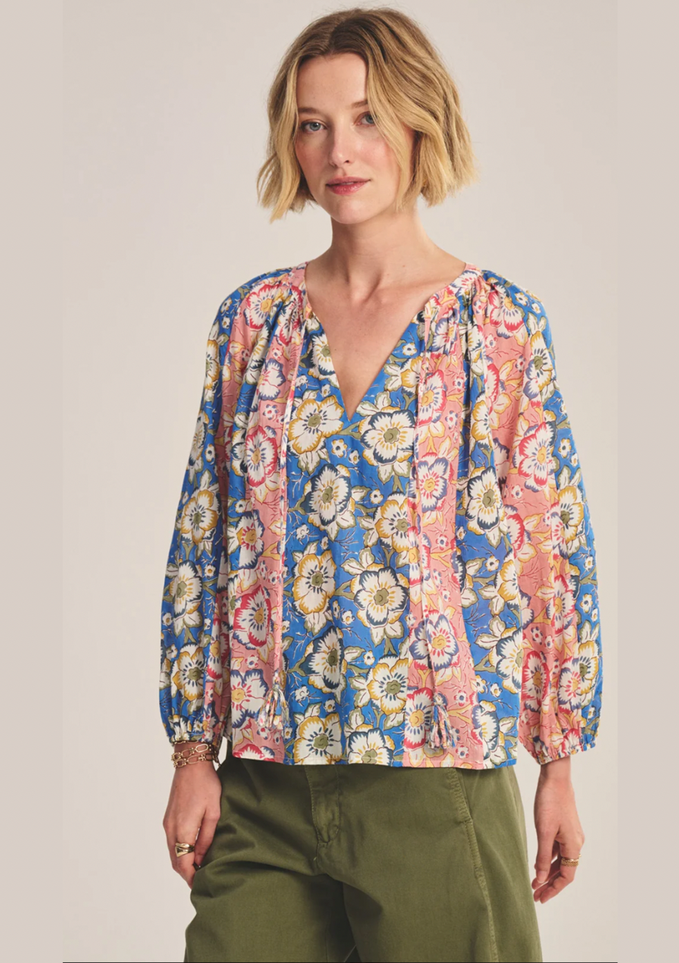 Woman wearing a colorful floral blouse against a plain background