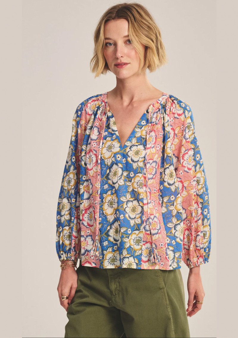 Woman wearing a colorful floral blouse against a plain background