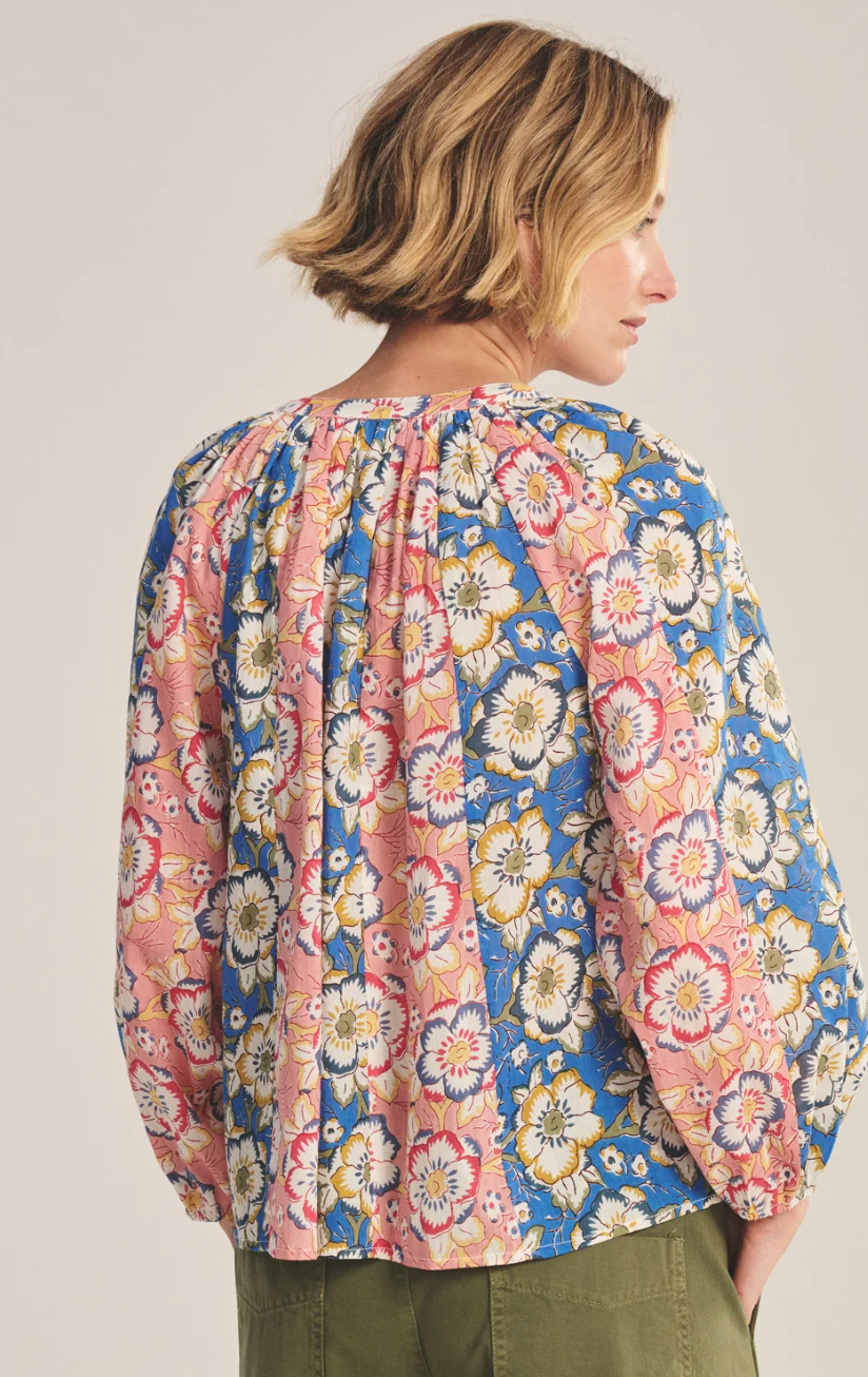 Woman wearing a colorful floral blouse against a plain background