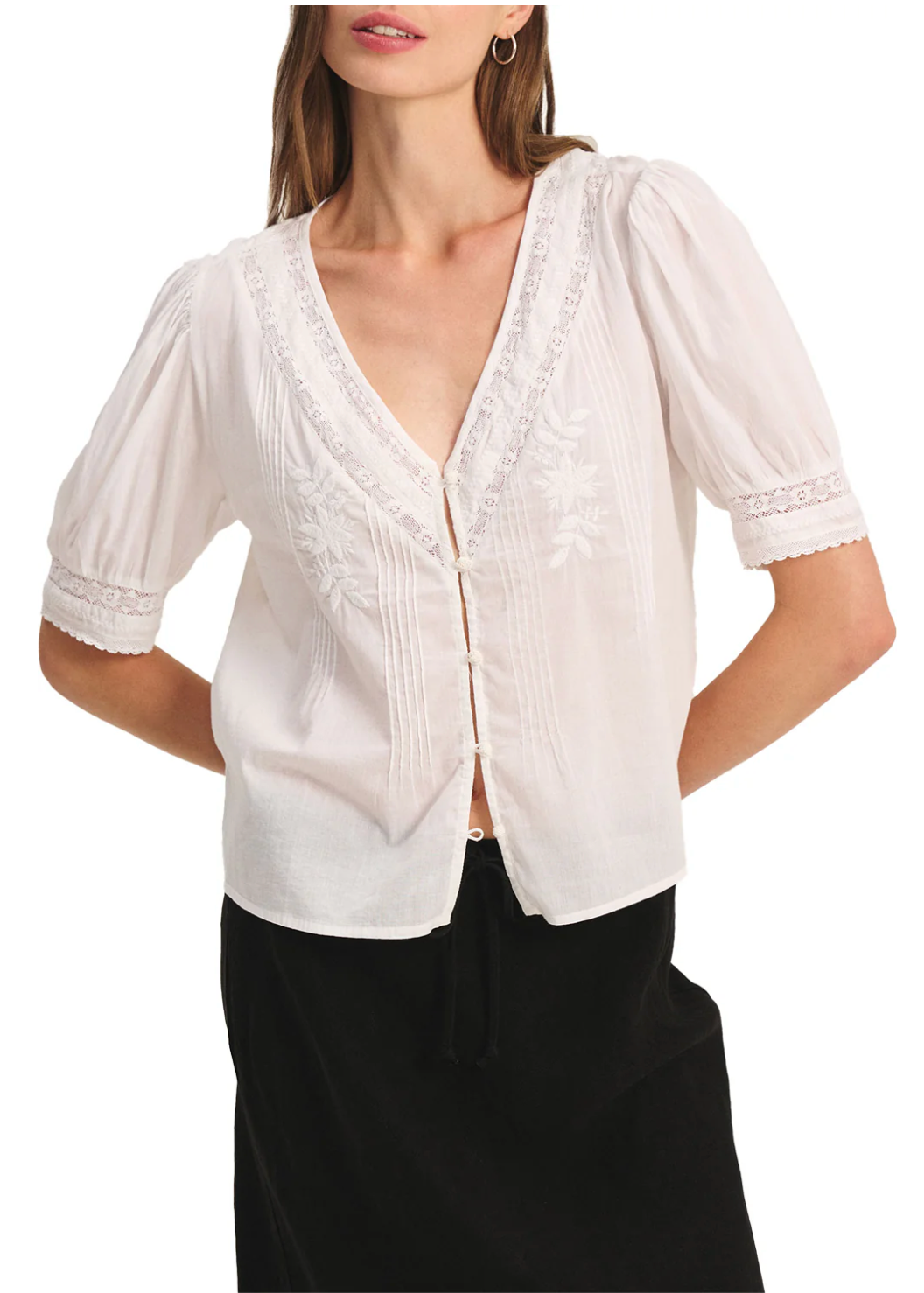 Woman wearing a white blouse with lace details on a white background