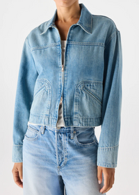 Person wearing a light blue denim jacket and jeans on a white background