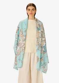 Woman wearing a light blue floral patterned scarf on a white background