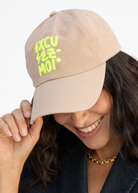 Person wearing a beige cap with green text on a white background