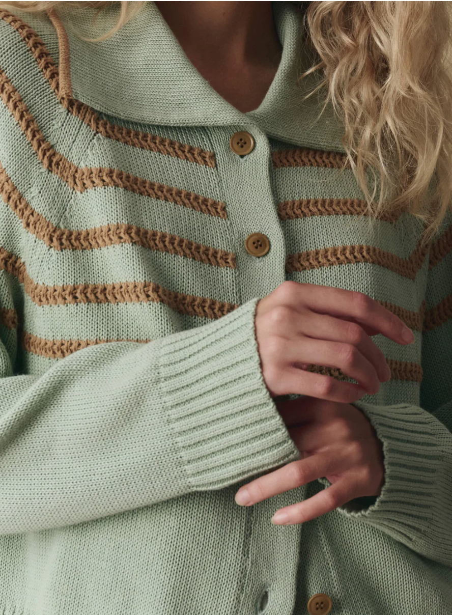 Close-up of a person wearing a green and brown striped sweater with a blurred background