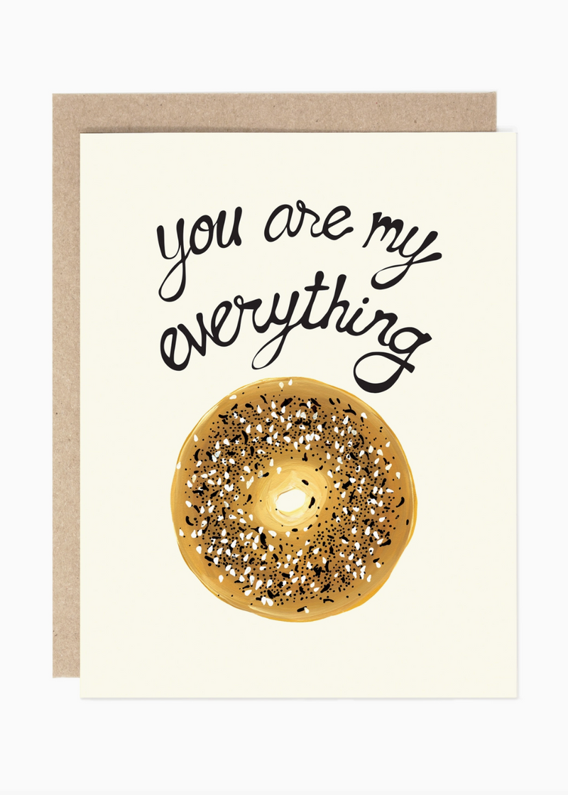 A greeting card with a kraft envelope, featuring the phrase 'you are my everything' in black script above a watercolor-style glazed donut with sprinkles on an off-white card background.