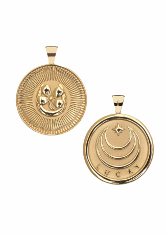 Two gold-toned round pendant charms shown on a plain white background, one displaying a raised three-eyed symbol in a sunburst design and the other showing a crescent moon and star design with the word 'LUCKY' at the bottom.