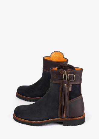 A pair of dark brown and navy suede ankle boots with leather straps, buckles, and tassels, set against a plain white background.