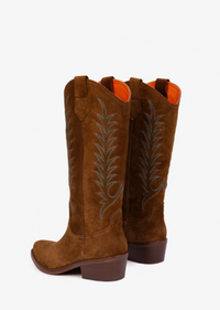 A pair of brown suede cowboy boots with blue embroidered leaf patterns and orange lining, shown from a rear three-quarter angle on a white background.