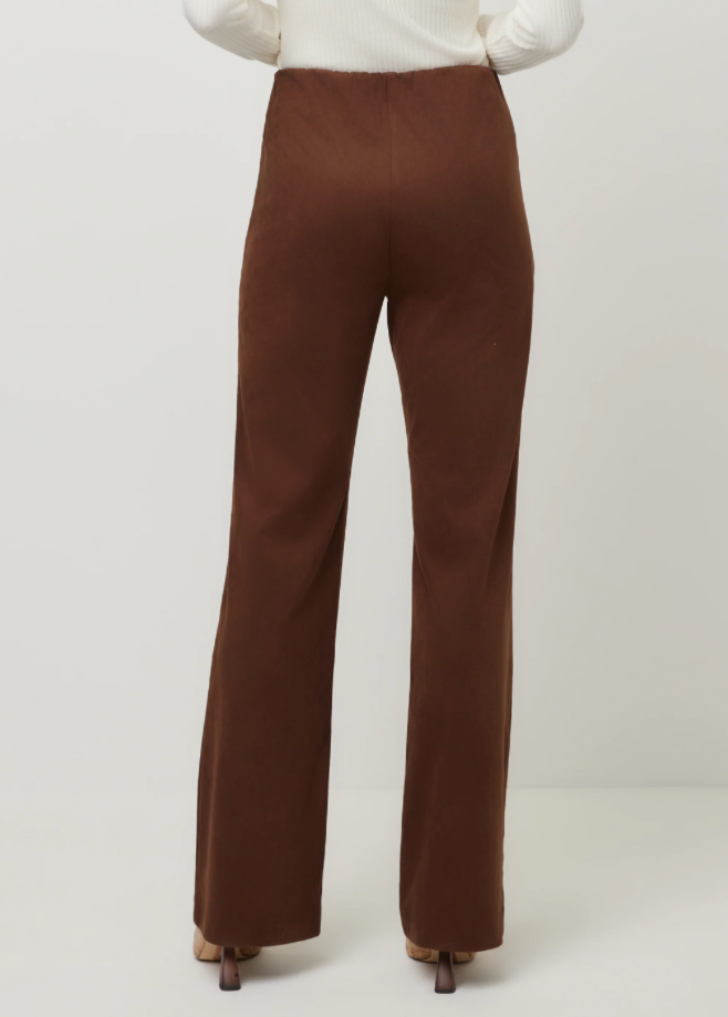 A person shown from the back wearing high-waisted, wide-leg brown pants with a white ribbed top and brown heels, against a plain light gray studio background.