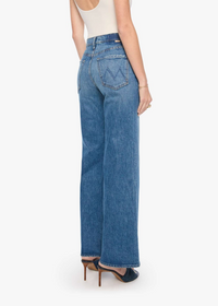 A model shown from the back wearing a pair of blue wide-leg jeans, a white sleeveless top, and dark heeled sandals against a plain white studio background.