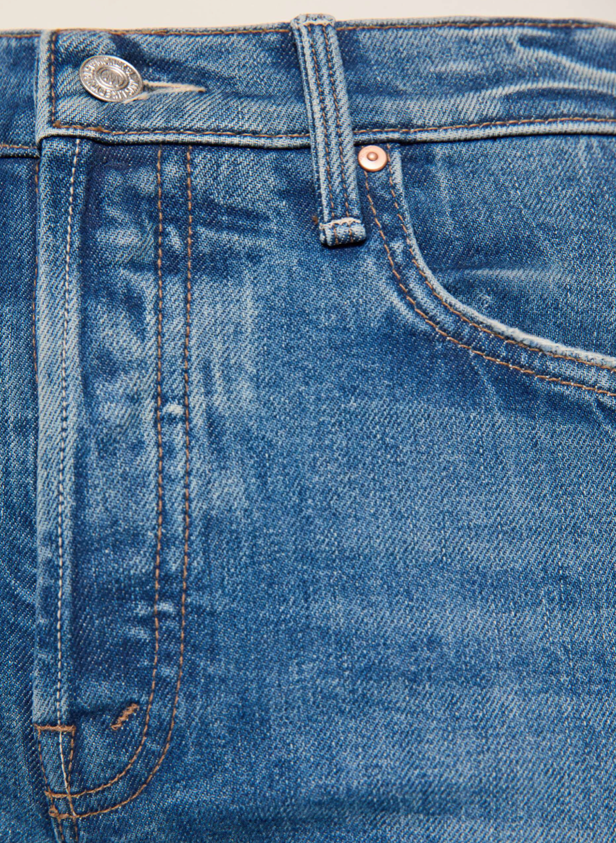 Close-up of blue denim jeans showing the waistband, belt loops, front pocket, and stitching details.