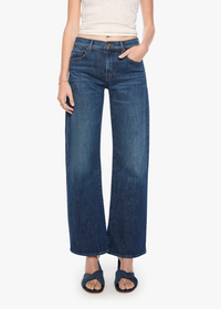 A model wearing a pair of dark blue wide-leg cropped jeans, styled with a cream ribbed tank top and dark blue slide sandals, against a plain white studio background.