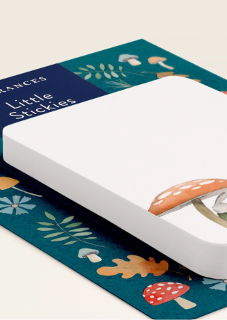 A white rectangular pad of Little Stickies sticky notes placed on top of a decorative teal paper mat with illustrated mushrooms, leaves, and autumn leaves. The brand name 'Frances' and product name 'Little Stickies' are visible on the top-left corner of the mat.