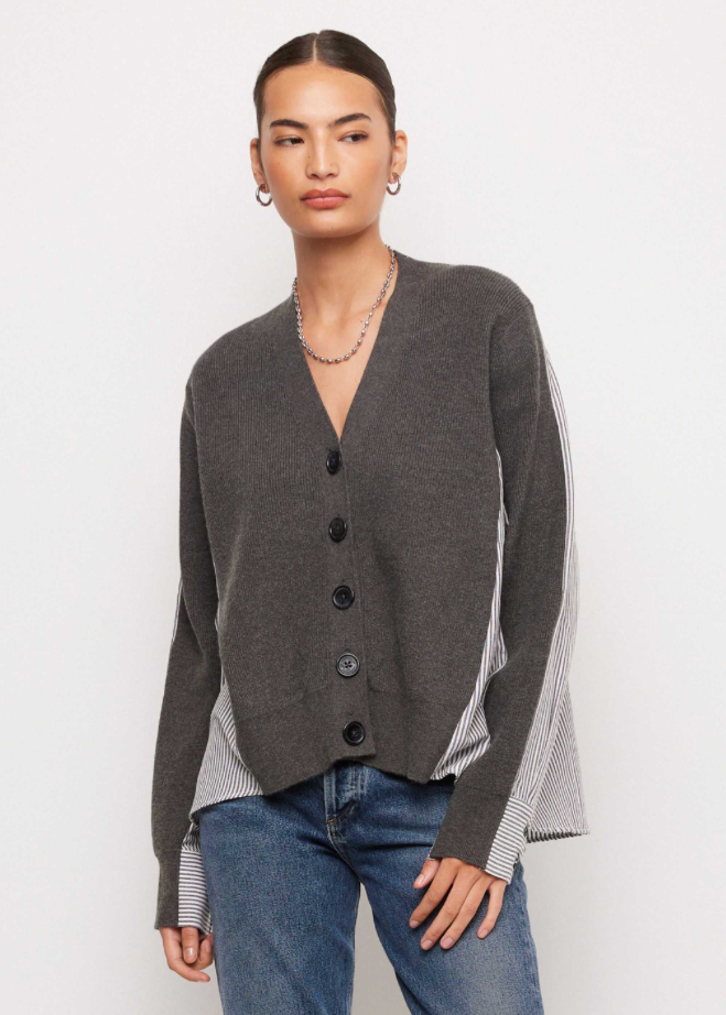 A model wearing a dark gray button-up cardigan with striped side panels and blue jeans, photographed against a plain light gray studio background.